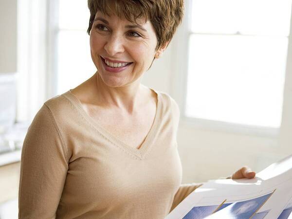 A woman smiling while standing in a bright sunlit office.