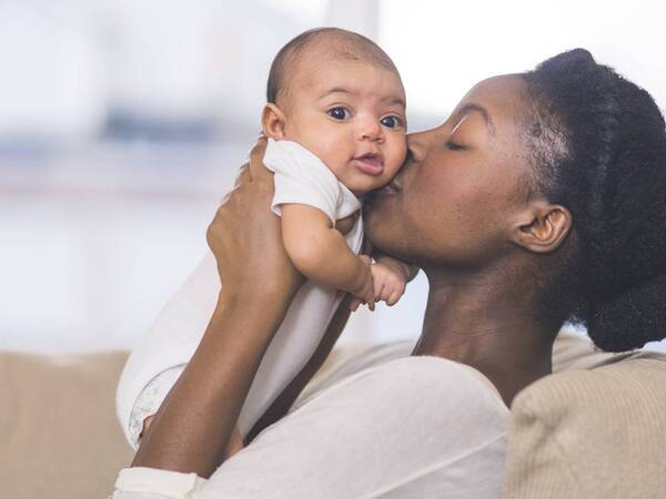 A woman holds an infant close to her face, representing healthy bonding and other aspects of parenting Scripps can help you with.