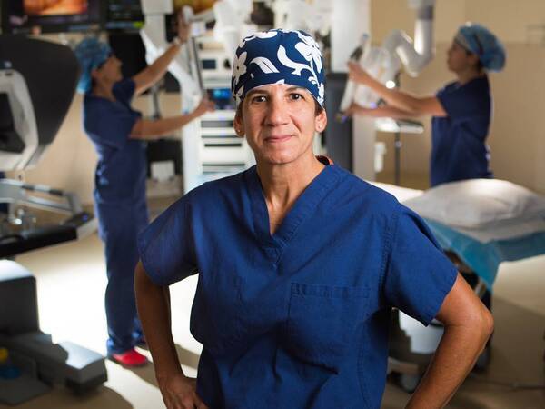 Dr. Carol Salem stands in a Scripps operating room while a team uses a robotic surgical system.