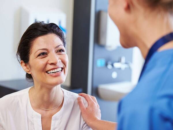 A smiling middle-aged woman talks to her doctor, representing the expert and compassionate thyroid disease treatment at Scripps.