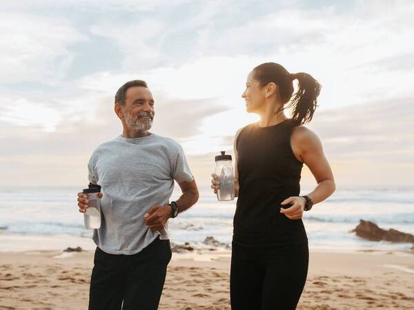 An older man and woman exercise at the beach representing a quicker recovery from outpatient or ambulatory surgery that doesn't require a hospital stay.