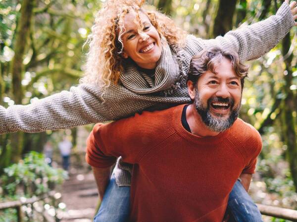 A mature man carrying his partner on his back illustrates life when you can effectively manage your orthopedic pain.